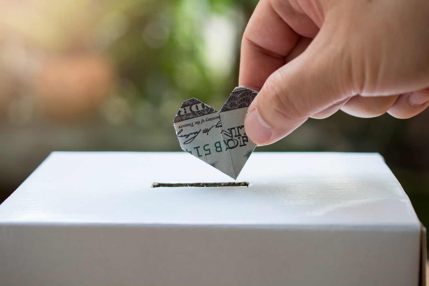 man puts dollar heart in a donation box